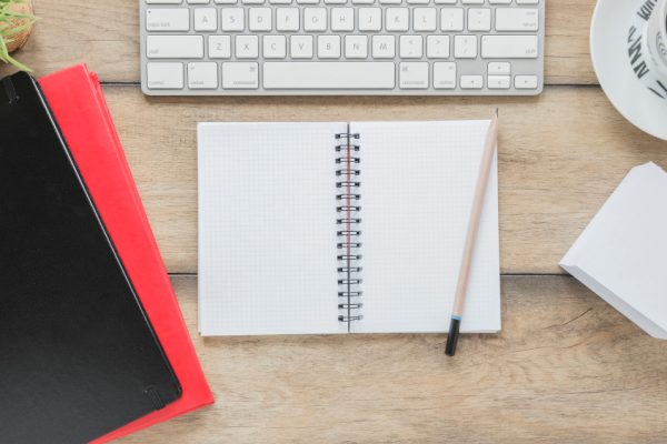 opened-notepad-stationery-near-keyboard-coffee-cup